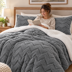 Woman reading in bed under a grey sherpa comforter set